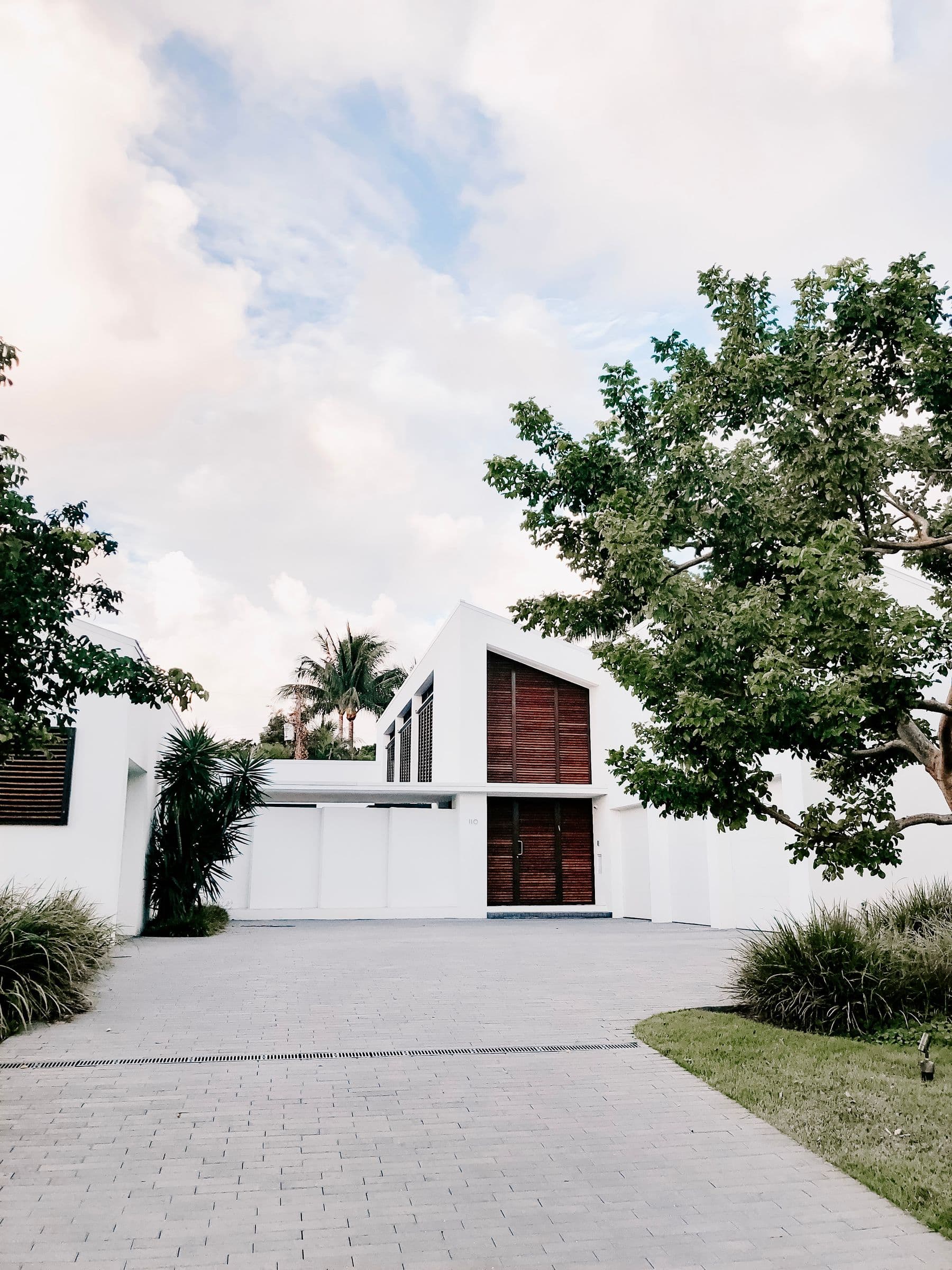 A modern white house with dark stained wood slats at the entry and gable