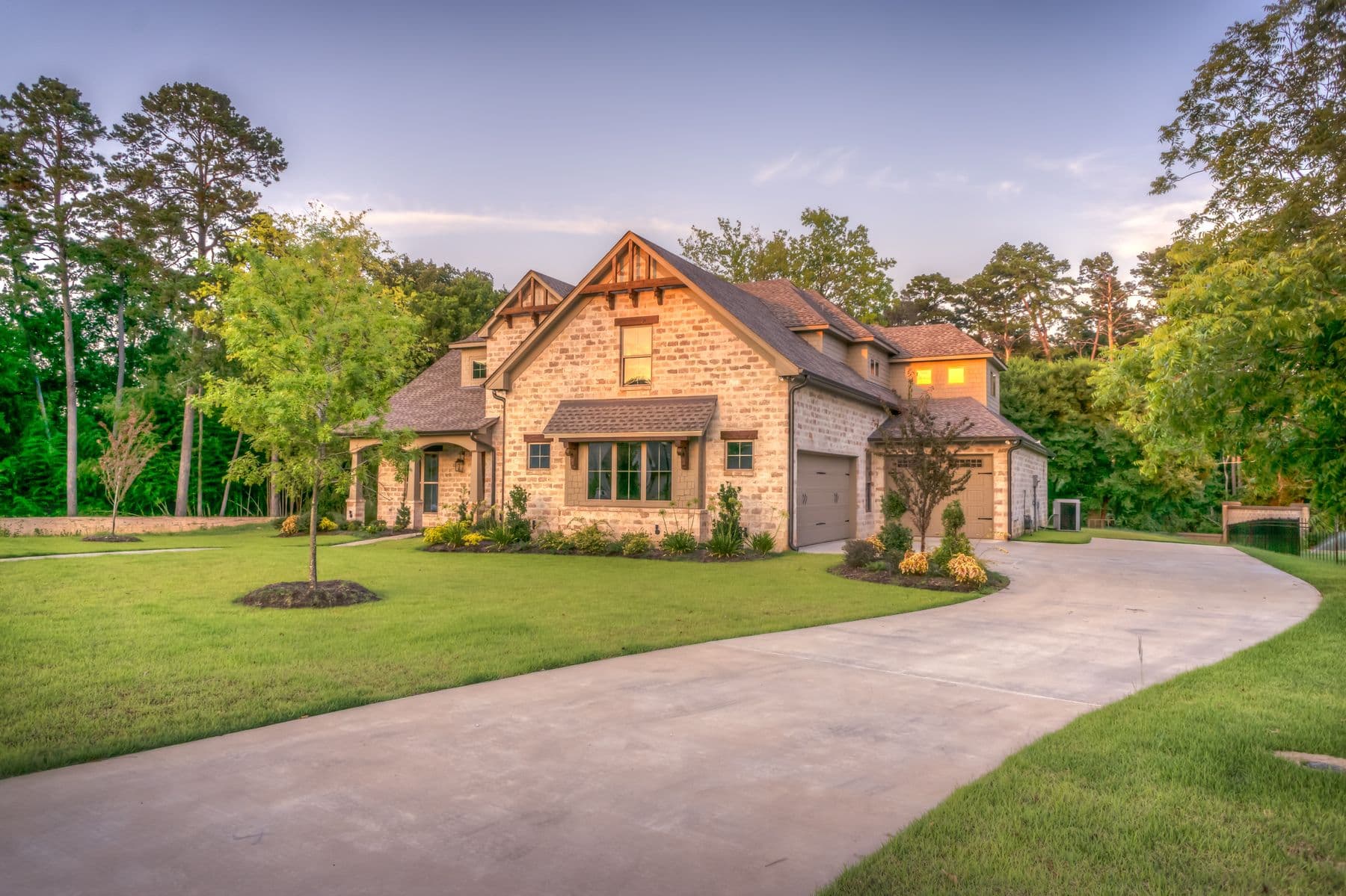 A large craftsman-style house at dusk with wood-shingled gables